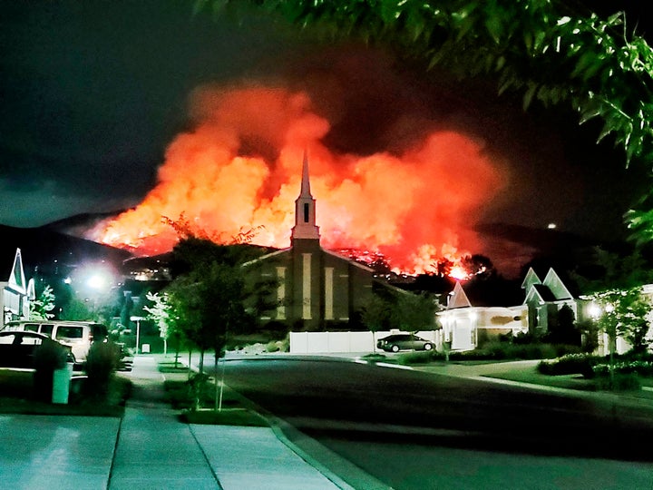 The Traverse fire burns behind homes in Lehi, Utah, early Sunday morning. Officials say fireworks caused the wildfire and for
