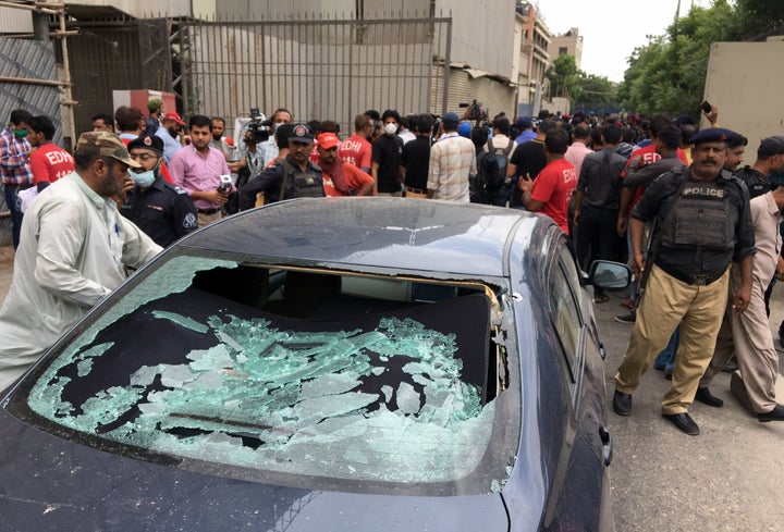 A plainclothes police officer (L) surveys the site of an attack at the Pakistan Stocks Exchange entrance in Karachi June 29, 2020.