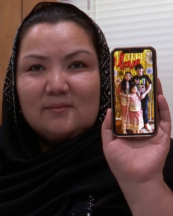 In this image from video, Zumret Dawut, a Uighur woman from China's far western Xinjiang region, holds a phone with a picture of her kids at her home in Woodbridge, Va., on June 15, 2020. She says in China, a doctor tied her fallopian tubes. After waking from the anesthesia, she felt her womb ache, as though it was missing something. “I was so angry. I wanted another son,” she said. 