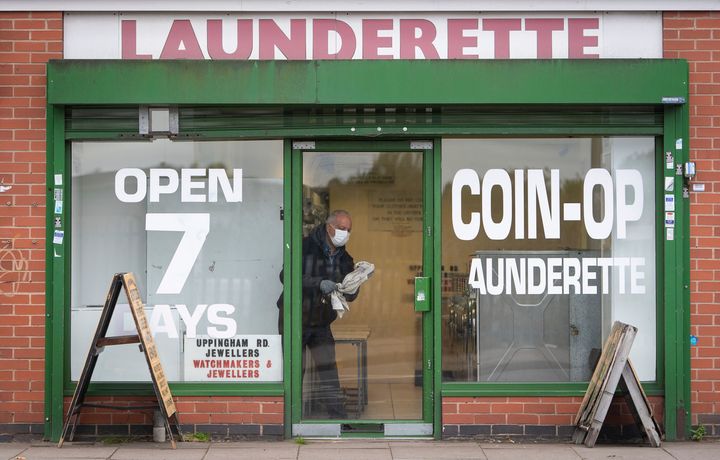 A man cleans the windows of a launderette in Leicester, England.