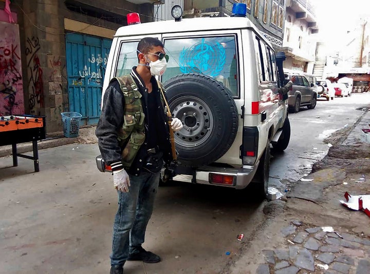 This May 2020 photo provided by a Yemeni community activist shows a man waiting for an ambulance to collect the body of a COVID-19 victim after medics declined to take the body in the Houthi-controlled city of Ibb, Yemen.