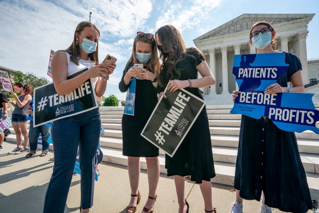 Anti-abortion activists wait in vain outside the Supreme Court for a decision Thursday. Roberts would...