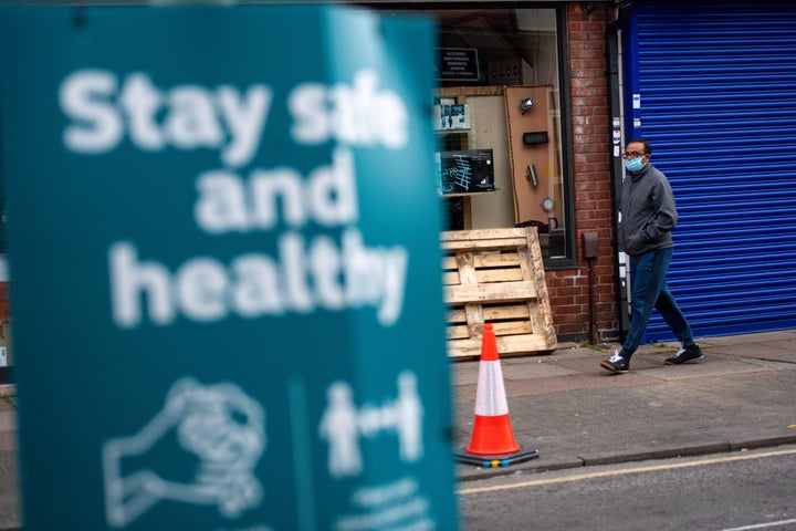 A man wearing PPE walks down a street in the North Evington area of Leicester