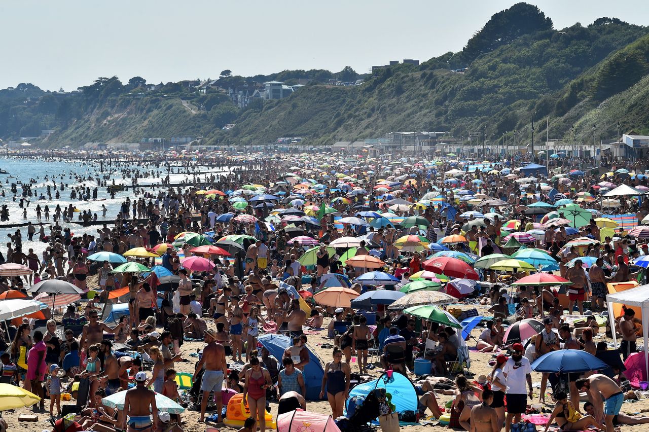 Beachgoers enjoy the sunshine as they sunbathe and swim on Bournemouth Beach in southern England on June 25.