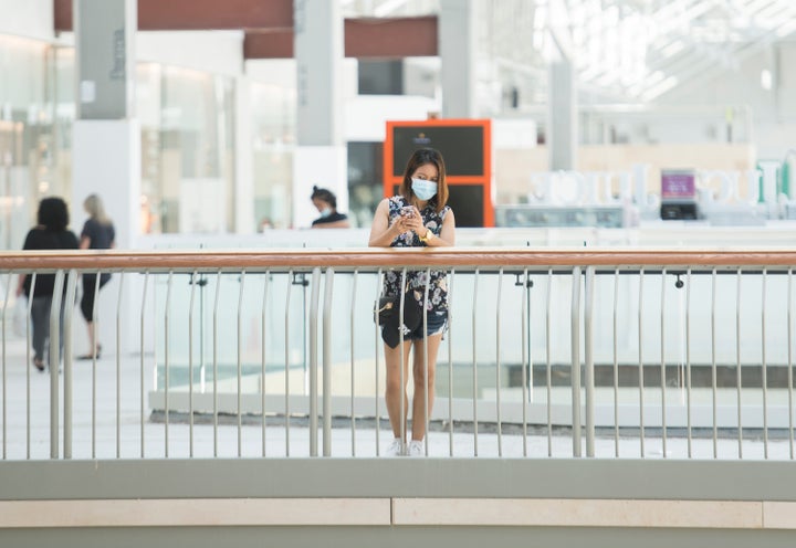 A woman wears a face mask as she looks on at an open shopping mall in Montreal on June 20, 2020.