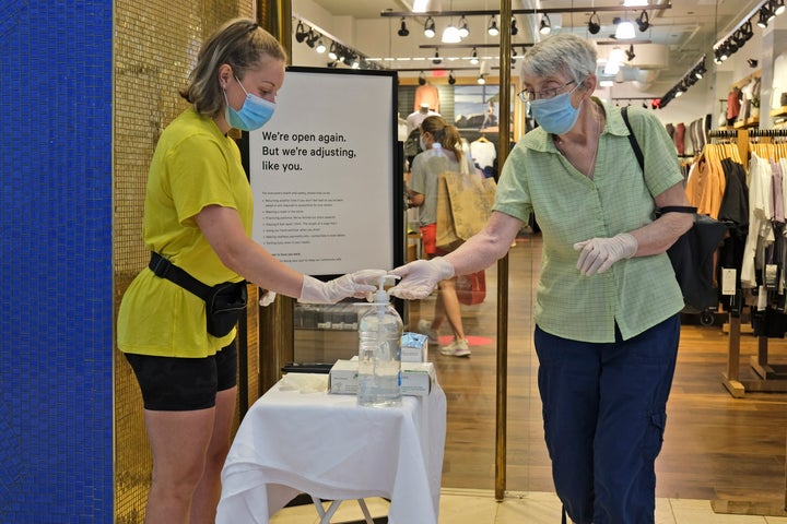 Meghan Griffin offers masks, gloves and hand sanitizer in front of a store Monday at the Garden State Plaza mall in Paramus, New Jersey. New Jersey's indoor shopping malls reopened on Monday from their COVID-19 pause. 