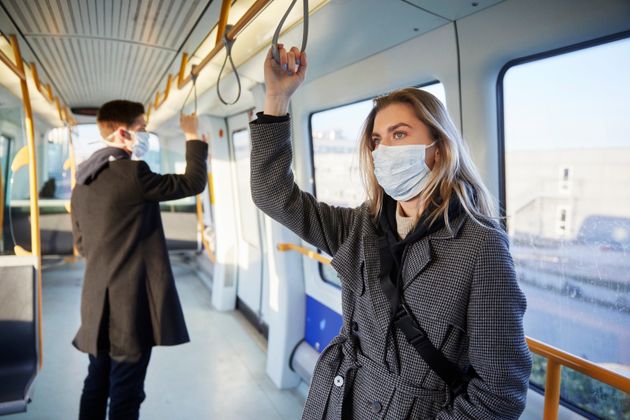 Young woman inside train, wearing a virus protective face mask