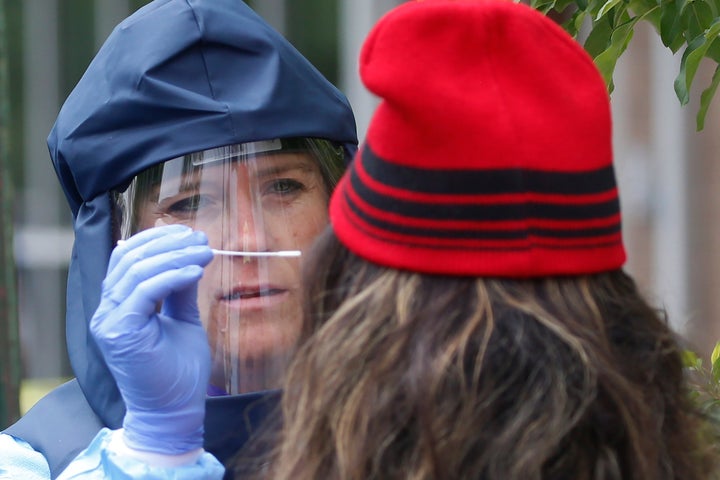 A Salt Lake County Health Department public health nurse performs a COVID-19 test outside the department's offices in Salt La