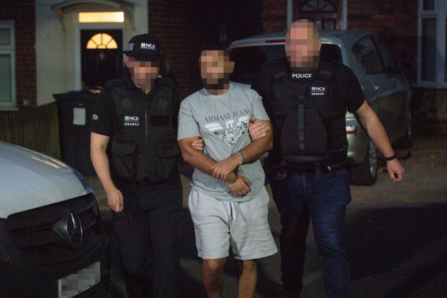 A man is led away by officers after he was detained during a raid by the National Crime Agency and police on a property in Birmingham on June 26  in relation to an investigation on Encrochat.