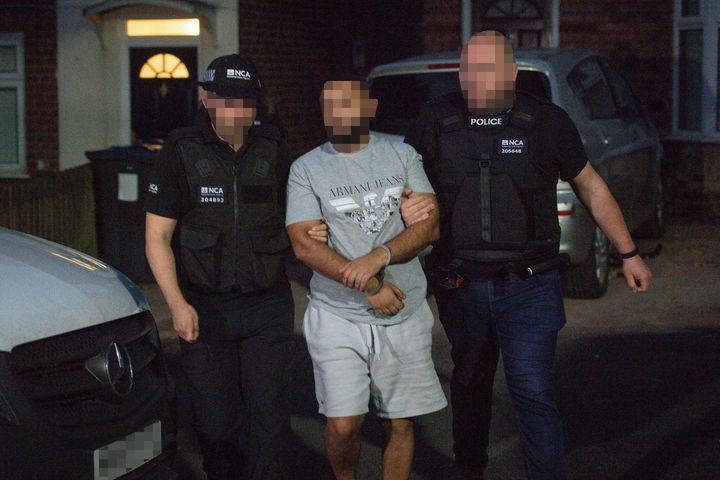 A man is led away by officers after he was detained during a raid by the National Crime Agency and police on a property in Birmingham on June 26 in relation to an investigation on Encrochat.