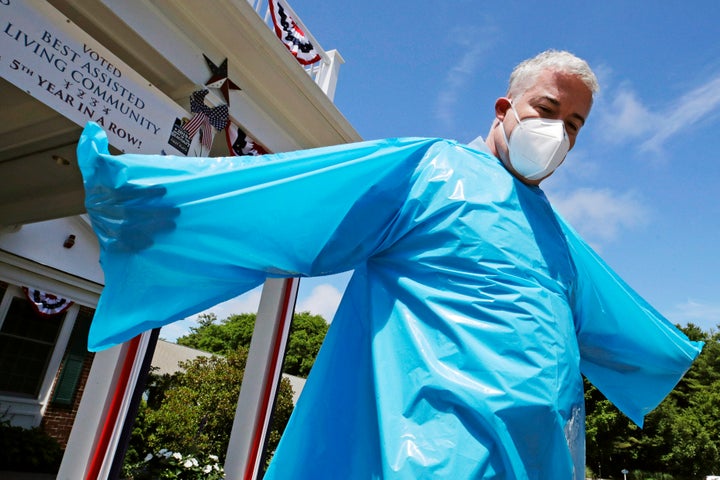 Williams demonstrates the lack of hand holes in a FEMA gown. Facilities are not using the items they received from the agency