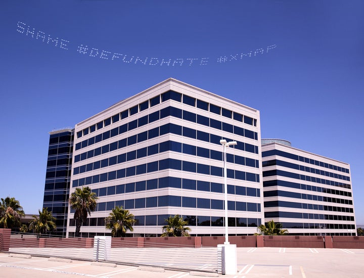 The skytyped phrase "#SHAME #DEFUND HATE" chosen by artist Cassils is seen over the Geo Group Headquarters during the In Plai