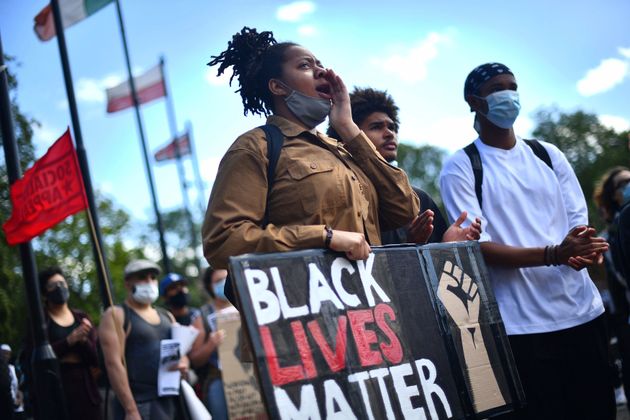 People hold placards, during an All Black Lives UK protest in London.