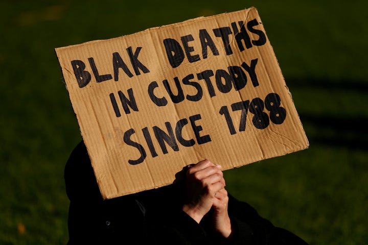 SYDNEY, AUSTRALIA - JULY 05: A man holds up a sign during a rally against Black Deaths in Custody in The Domain on July 05, 2020 in Sydney, Australia.The rally was organised to protest against Aboriginal and Torres Strait Islander deaths in custody and in solidarity with the global Black Lives Matter movement. (Photo by Don Arnold/Getty Images)