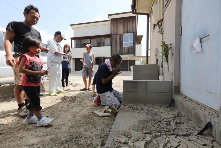 大規模浸水で51人が死亡した岡山県倉敷市真備町。浸水被害で亡くなった町内会長の自宅前で手を合わせる住民＝2018年8月6日、岡山県倉敷市真備町地区 