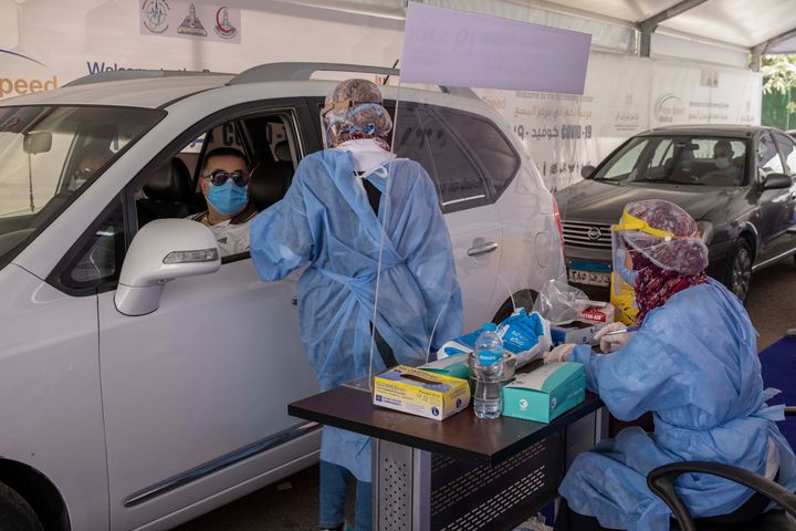 In this June 17, 2020 file photo, a health worker prepares to take swab samples from people queuing in their cars to test for the coronavirus at a drive-through COVID-19 screening center at Ain Shams University in Cairo, Egypt.
