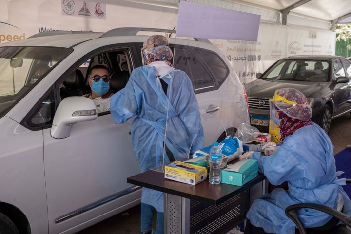 In this June 17, 2020 file photo, a health worker prepares to take swab samples from people queuing in their cars to test for