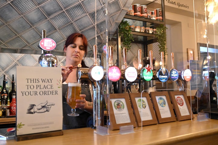 A staff member at the Wellington Pub pours drinks behind a protective screen on July 4 in Borehamwood, England.