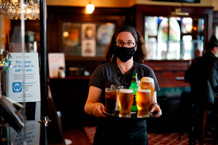 A member of bar staff wearing a face mask carries drinks inside the Wetherspoon pub, Goldengrove in Stratford in east London, on July 4.