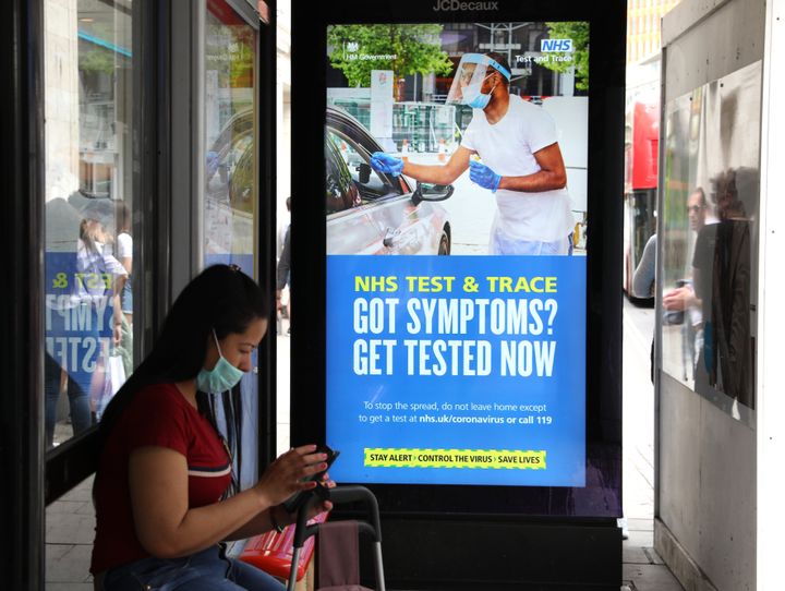 A screen on a bus stop displaying a NHS notice on test and trace on Oxford Street, London