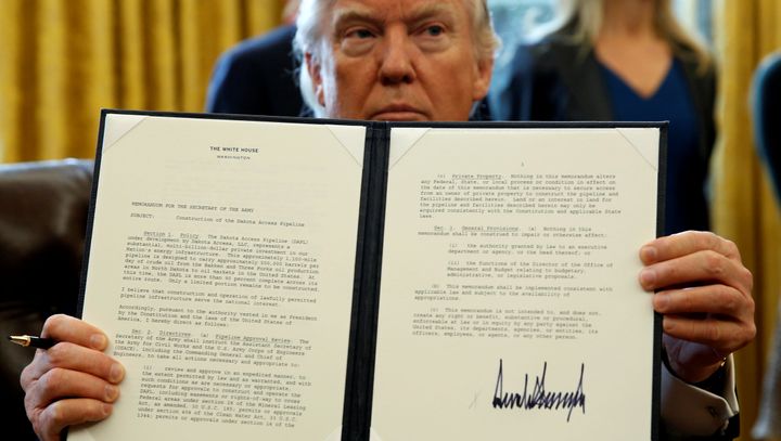 President Donald Trump holds up a signed executive order to advance construction of the Dakota Access pipeline at the White House on Jan. 24, 2017.