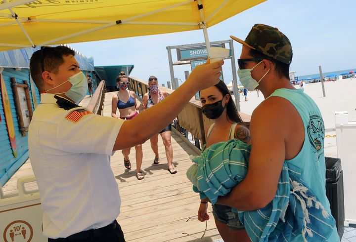 People wear face masks and undergo mandatory temperature checks before entering the pier on Independence Day in Cocoa Beach, Florida