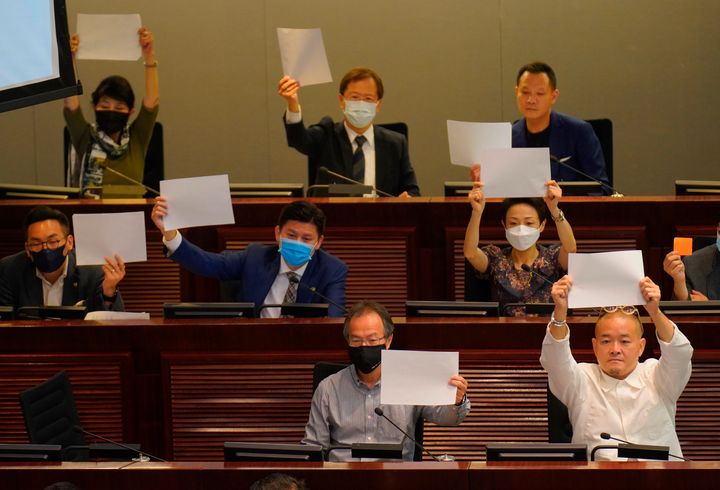 Pro-democracy lawmakers raise white papers to protest during a meeting to discuss the new national security law at the Legislative Council in Hong Kong on Tuesday.