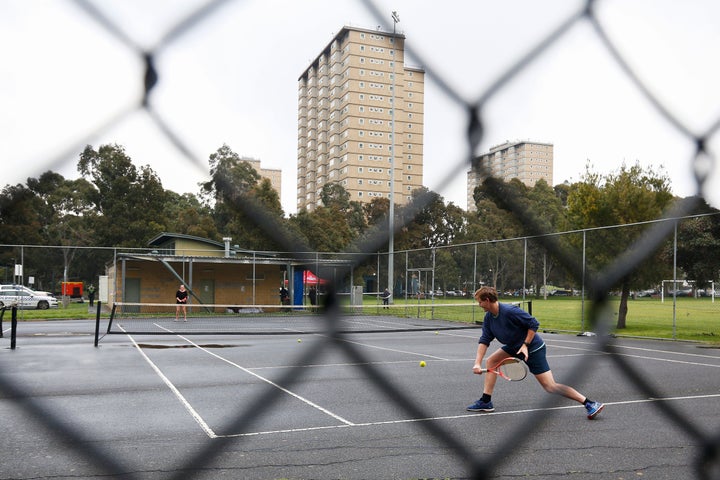 People play tennis near a block of public housing towers that residents have been banned from leaving, on Tuesday.