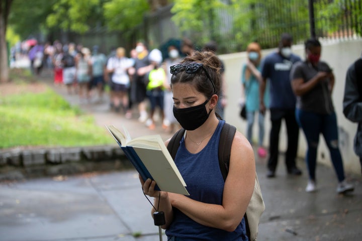 Kelsey Luker reads as she waits in line to vote on June 9 in Atlanta. Luker said she had been in line for almost two hours. Voters reported wait times of three hours.