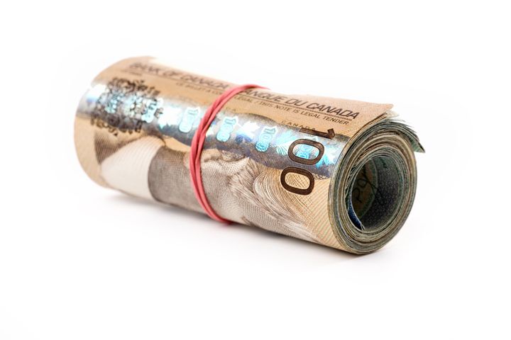 File photo of Canadian money wound up in a roll. The Parliamentary Budget Office estimates a six-month basic income program would cost at least $47.5 billion.