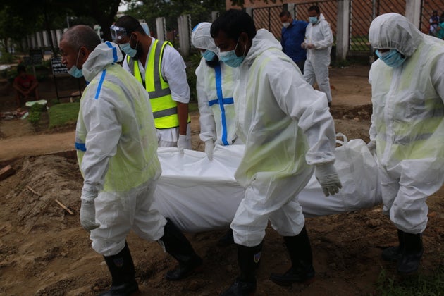 Volunteers wearing protective stuffs carry the body of a man who died from the COVID-19 coronavirus infections...