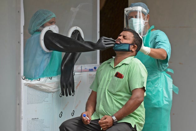 Health officials collect a swab sample from a man to test for COVID-19, at a testing centre in