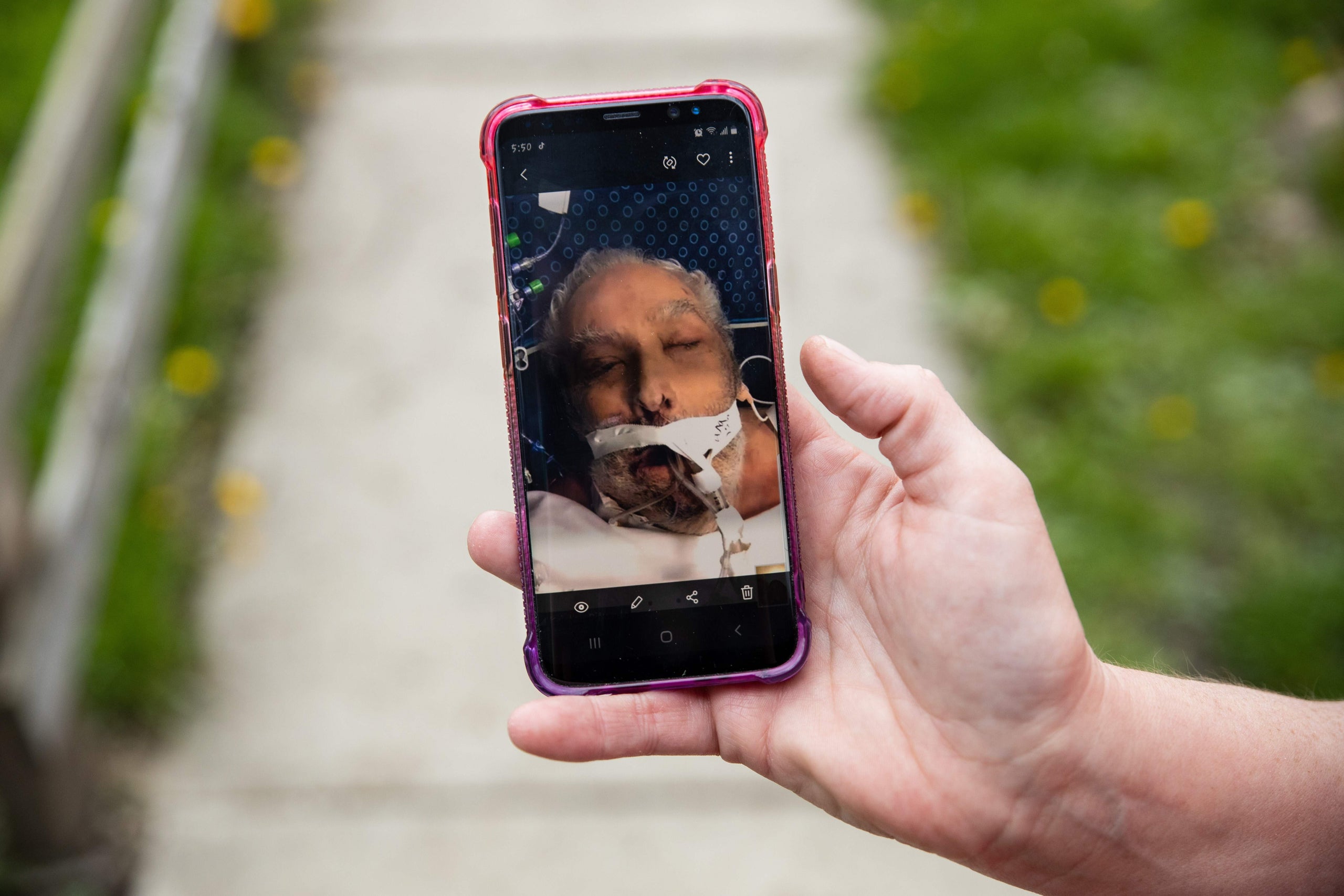 Christine Bevington holds a photo of her stepfather, Jesse Zeigler, taken as his family said goodbye on a video call before h