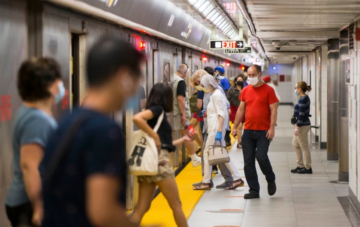 Passengers wearing face masks get on and off a train at a subway station in Toronto. We're all going to be wearing masks for a long time, so we need to figure out how to live with them.