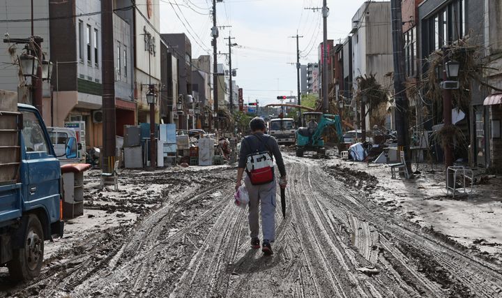 泥に覆われた道路を歩く男性＝8日午前、熊本県人吉市 