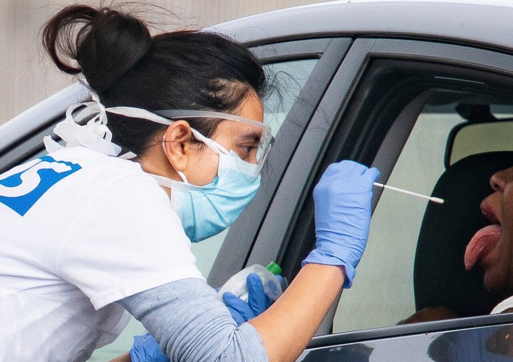 A medical worker takes a swab at a drive-in coronavirus testing facility at the Chessington World of Adventures Resort in Chessington.