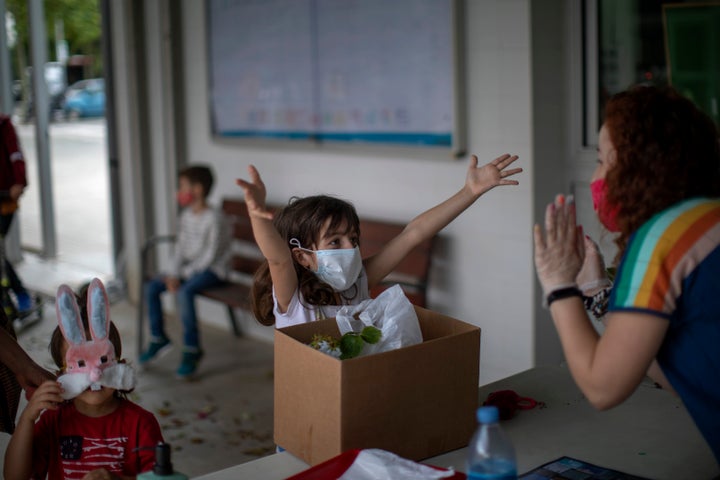 A primary school student gestures as if asking for a hug from her teacher at the end of the school year in Barcelona. 