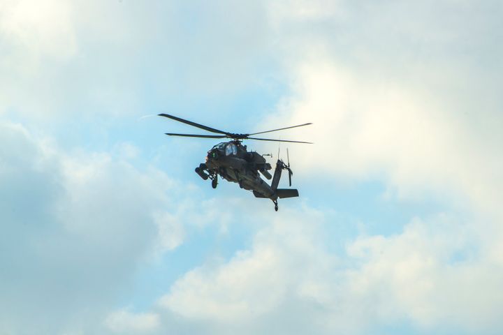 An Apache Helicopter Flying Over Blue Sky