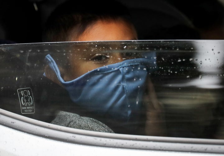 A boy wears a face mask as food is delivered to his family's truck at a food bank distribution center in Van Nuys, California, in April. At the time, organizers said they had distributed food for 1,500 families during the COVID-19 pandemic.