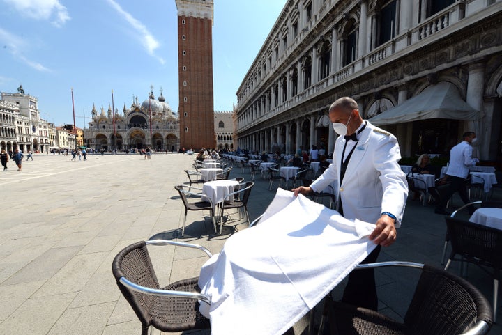 A waiter sets a table on June 12 at the terrace of the 18th Century Cafe Florian on St. Mark's Square in Venice, which reopens after being closed for three months during the country's lockdown.