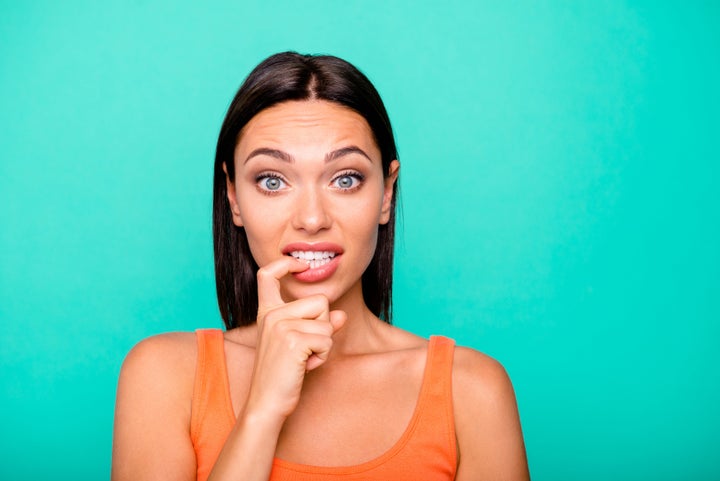 Close up photo portrait of depressed negative expressing nervous girl biting nails damaging new manicure isolated pastel background.