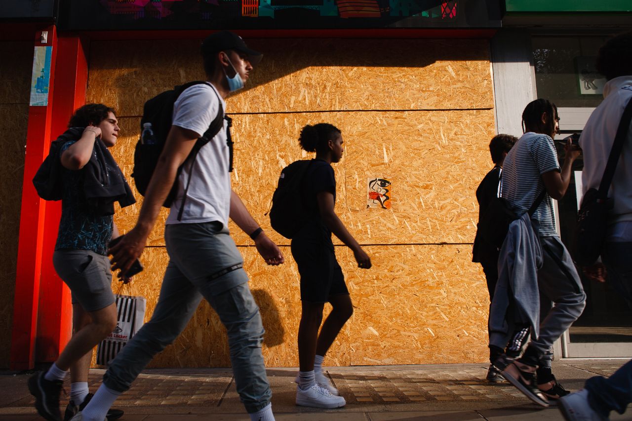 Young men walk past a boarded-up retail unit on Oxford Street in London.