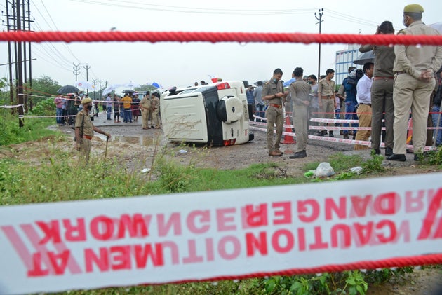 Policemen stand guard next to an overturned vehicle after the gangster Vikas Dubey was shot dead by police,...