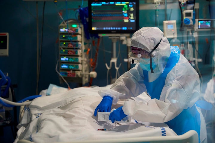 Un profesional sanitario toma una muestra de sangre a un enfermo de la covid-19 en la UCI del hospital del Mar de Barcelona. E