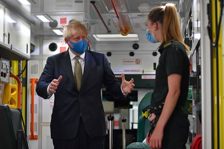 Prime minister Boris Johnson, wearing a face mask, talks with a paramedic as they stand inside the back of an ambulance during a visit to the headquarters of the London Ambulance Service NHS Trust in London.