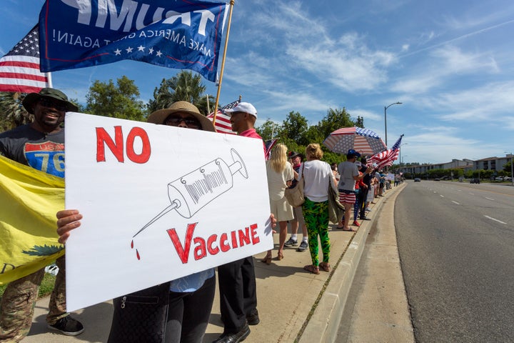 A protester holds an anti-vaccination sign as Trump supporters rally to reopen California. 