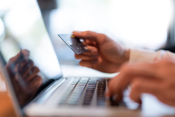 Man's hands holding credit card and typing on computer, close-up