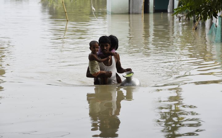  A man carries his children to a safer place in a flood-affected village of Kamrup district of Assam, India, on July 14, 2020. 