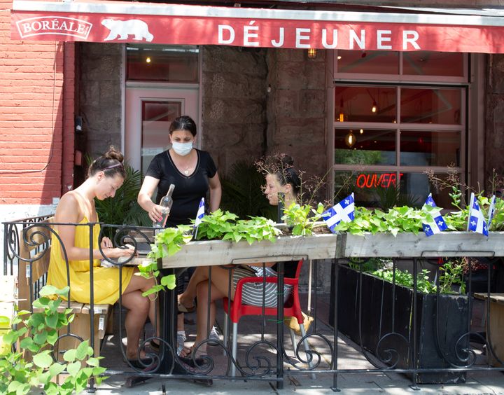 Patrons look at a menu at a restaurant on the first day after novel coronavirus restrictions were lifted to visit restaurants in Montreal on June 22, 2020.