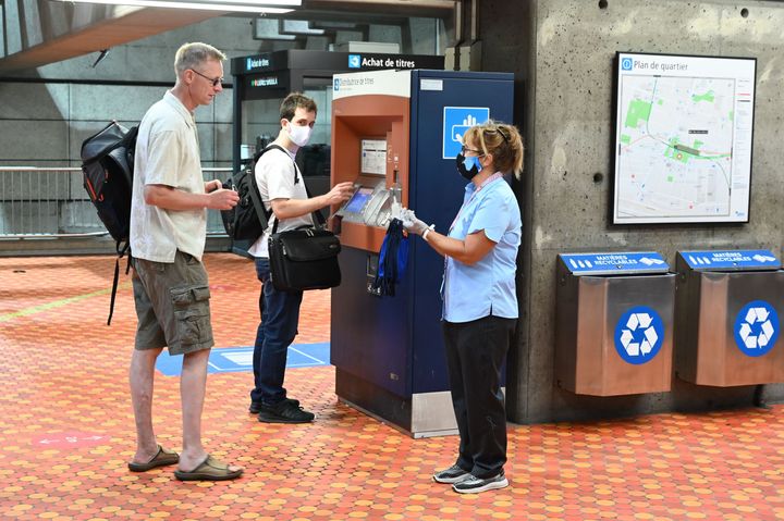 An employee of the Montreal metro offers free masks to traveller who don't have one with them at the Lionel Groulx station on July 13, 2020 as face coverings and masks become compulsory in all public transports in the Quebec province in Montreal.